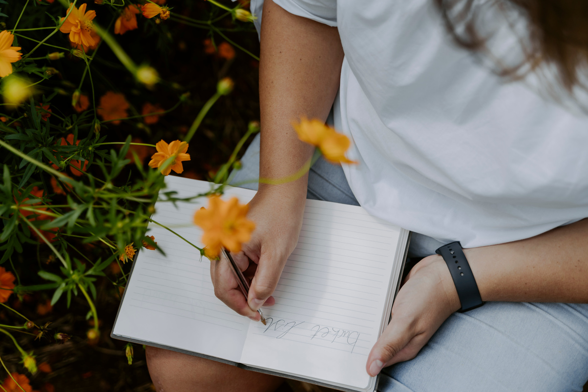 Woman Writing Bucket List on a Notebook Outdoors